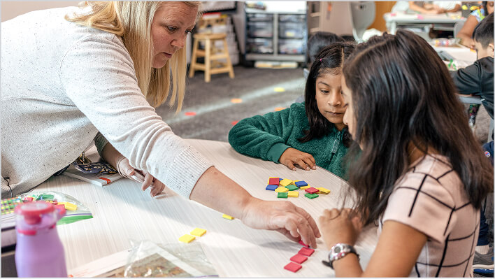 Teacher guiding a student through a hands-on K–5 math lesson