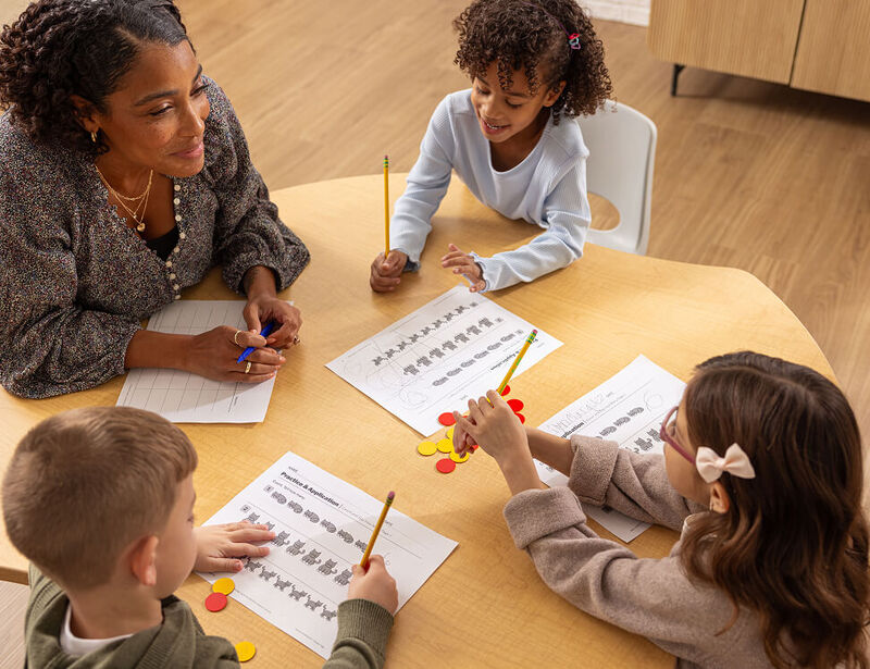 A teacher works through Pathways to Mastery assessments with three students